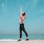 woman pointing at sky on seashore