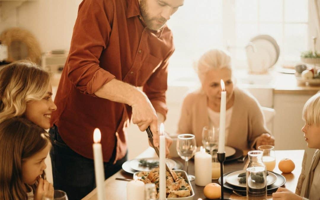 selective focus photography of man preparing food beside smiling women and kids