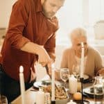 selective focus photography of man preparing food beside smiling women and kids