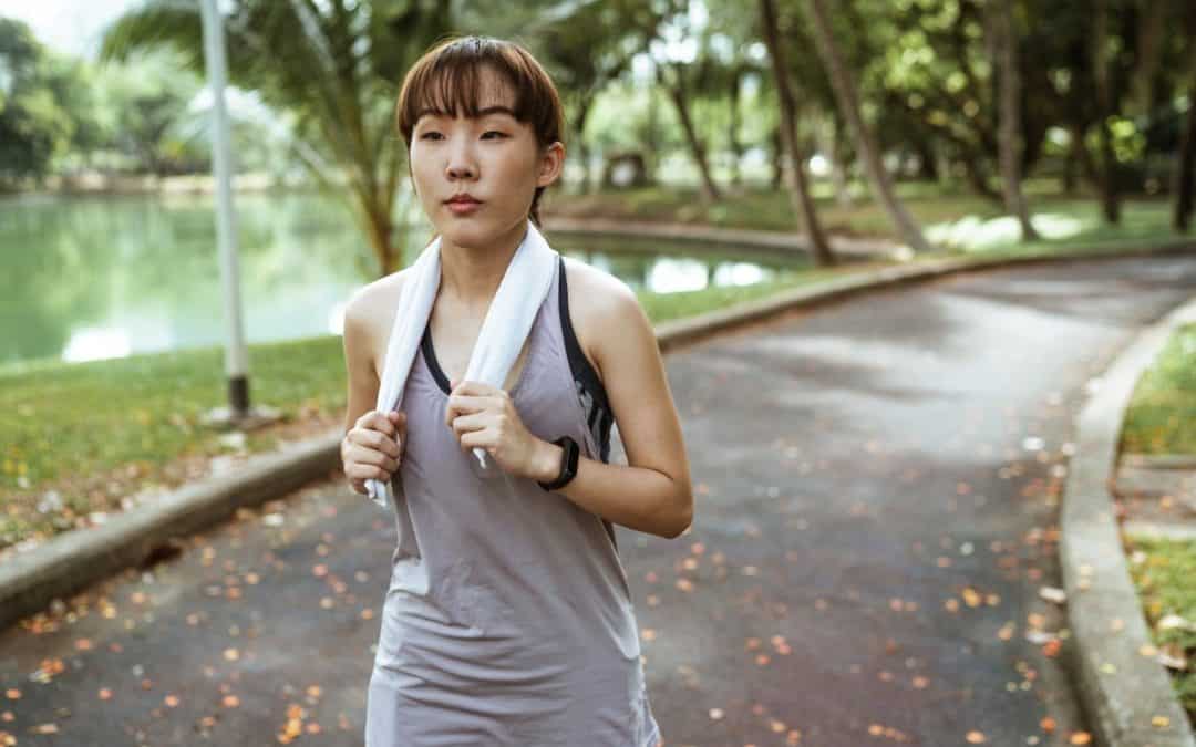 confident woman with towel running in park