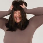 young obese woman rumpling hair with closed eyes in white studio