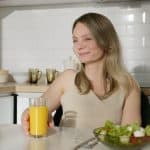 woman sitting by the table with an orange juice and vegetable salad