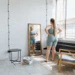 woman standing in front of a mirror near a window