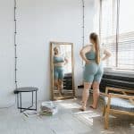 woman standing in front of a mirror near a window