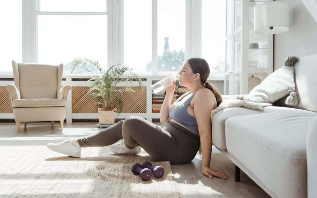 woman drinking water while sitting on the floor