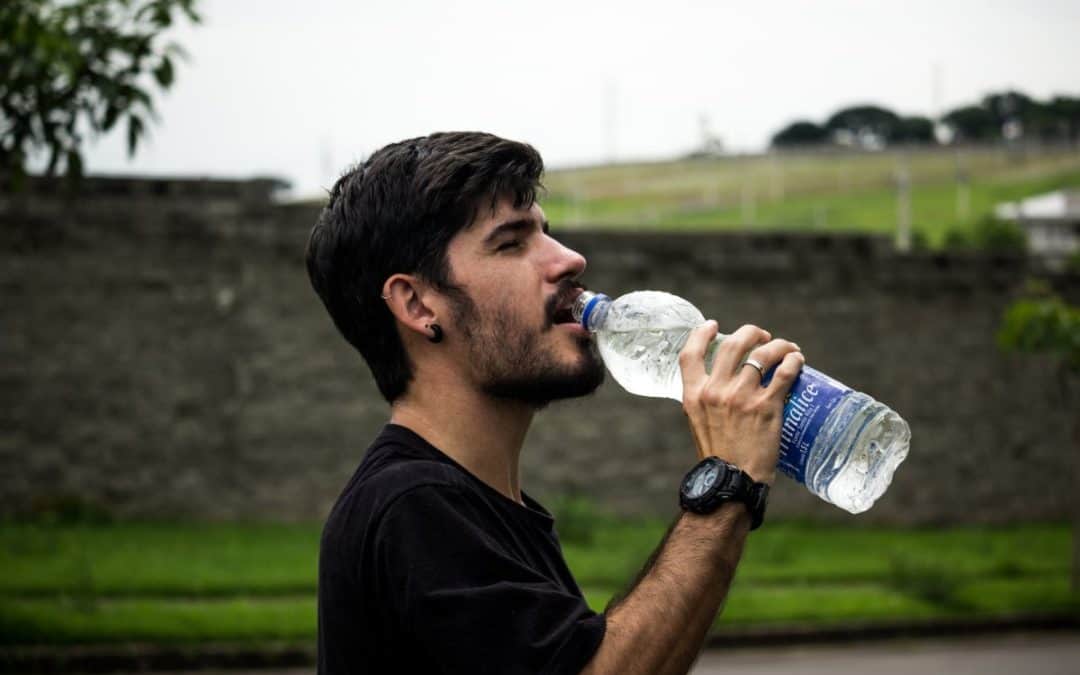 man wearing black shirt drinking water