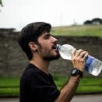 man wearing black shirt drinking water