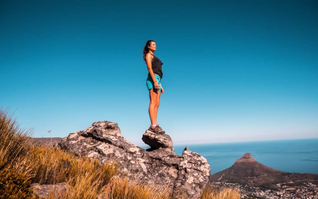 woman in black top and blue shorts on stone under blue sky