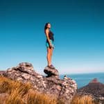 woman in black top and blue shorts on stone under blue sky