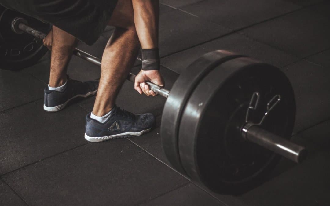 man in black reebok shoes about to carry barbell