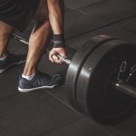 man in black reebok shoes about to carry barbell