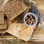 top-view-of-whole-grain-bread-and-hazelnut-in-bowl-with-protein-bar-on-chopping-board_sm