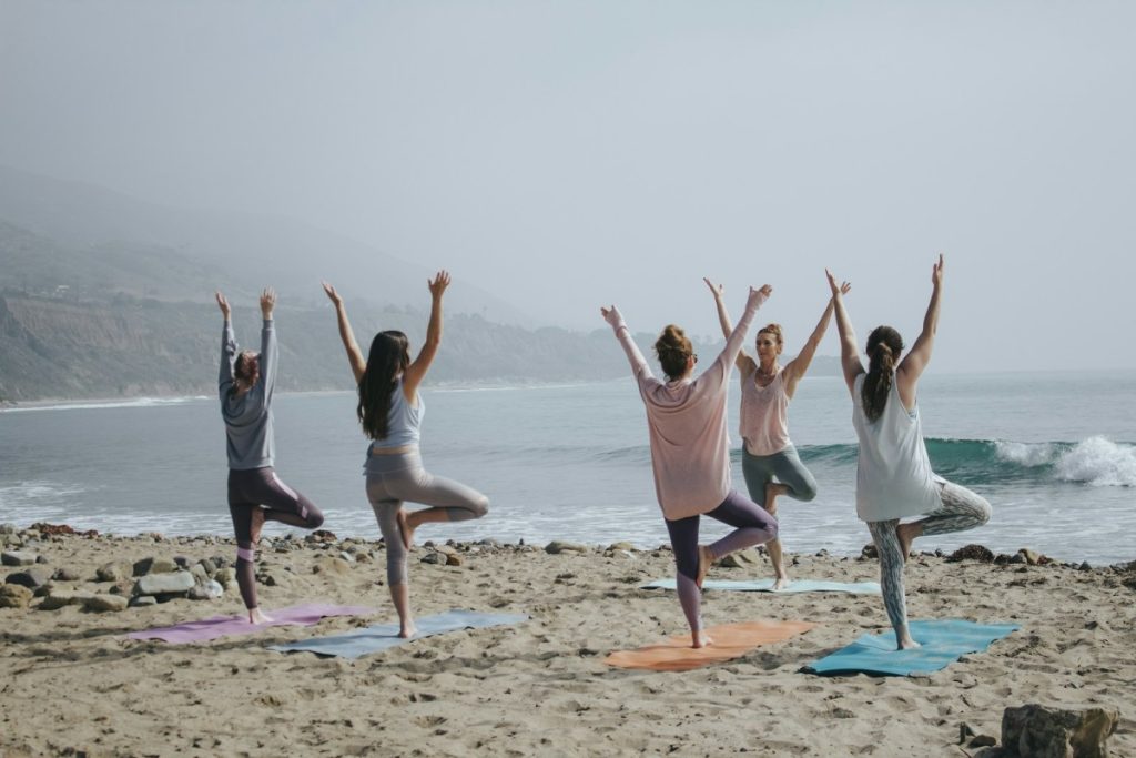 Yoga - five woman standing on seashore